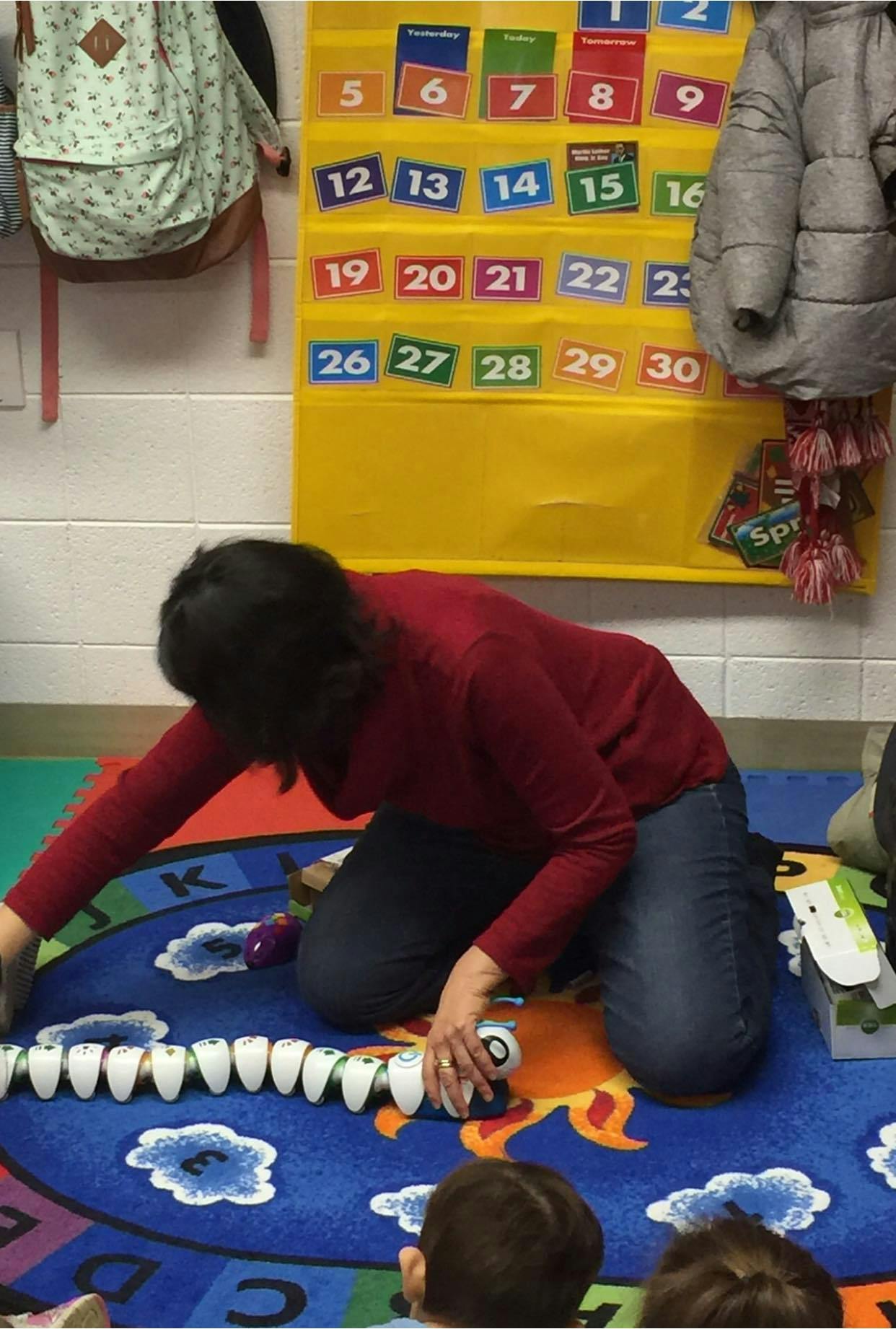 Person kneeling on a rug, playing with a toy