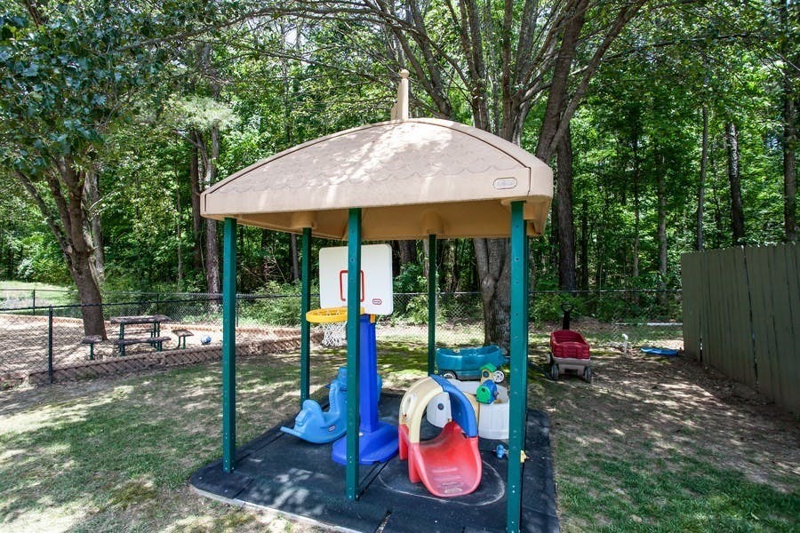 Playground structure with a slide and basketball hoop under a canopy