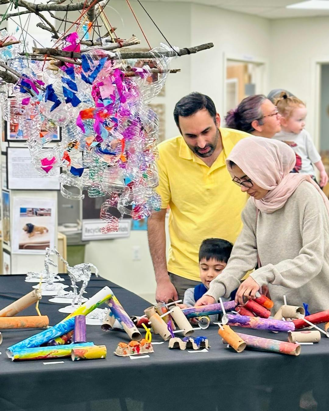 People viewing children's craft projects on a table