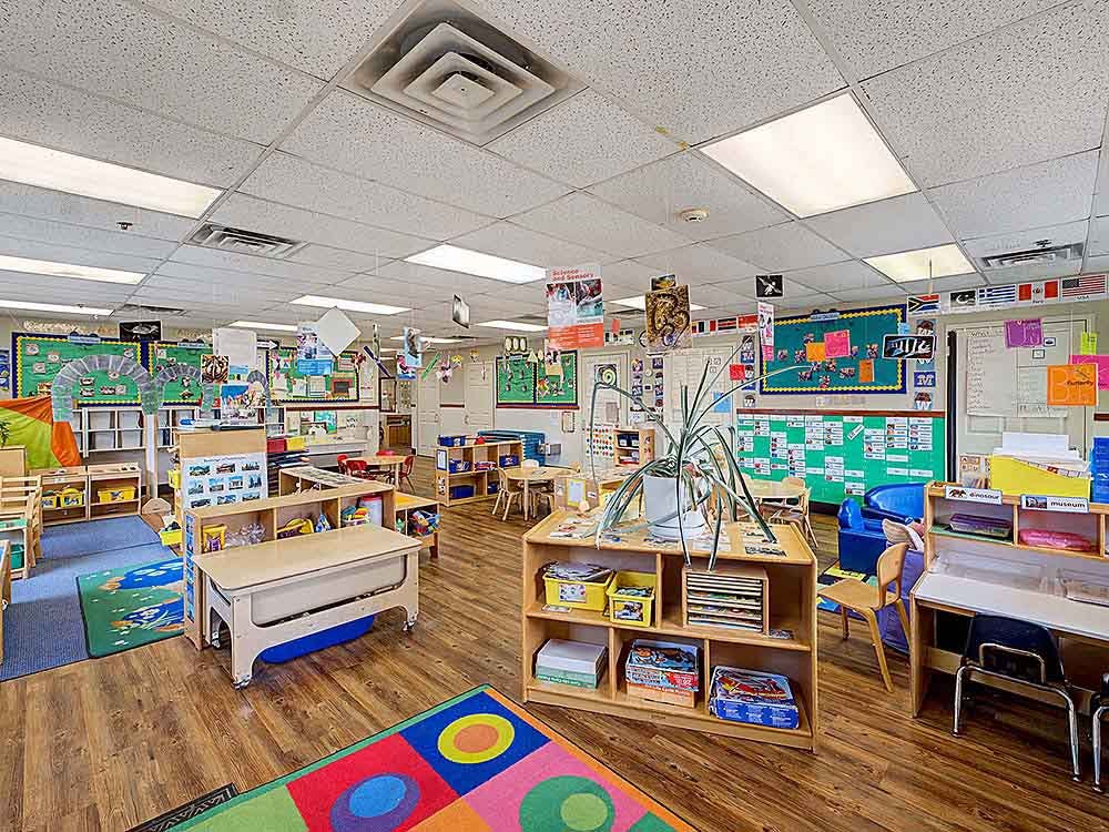 Empty classroom with colorful rugs, low tables, and educational materials