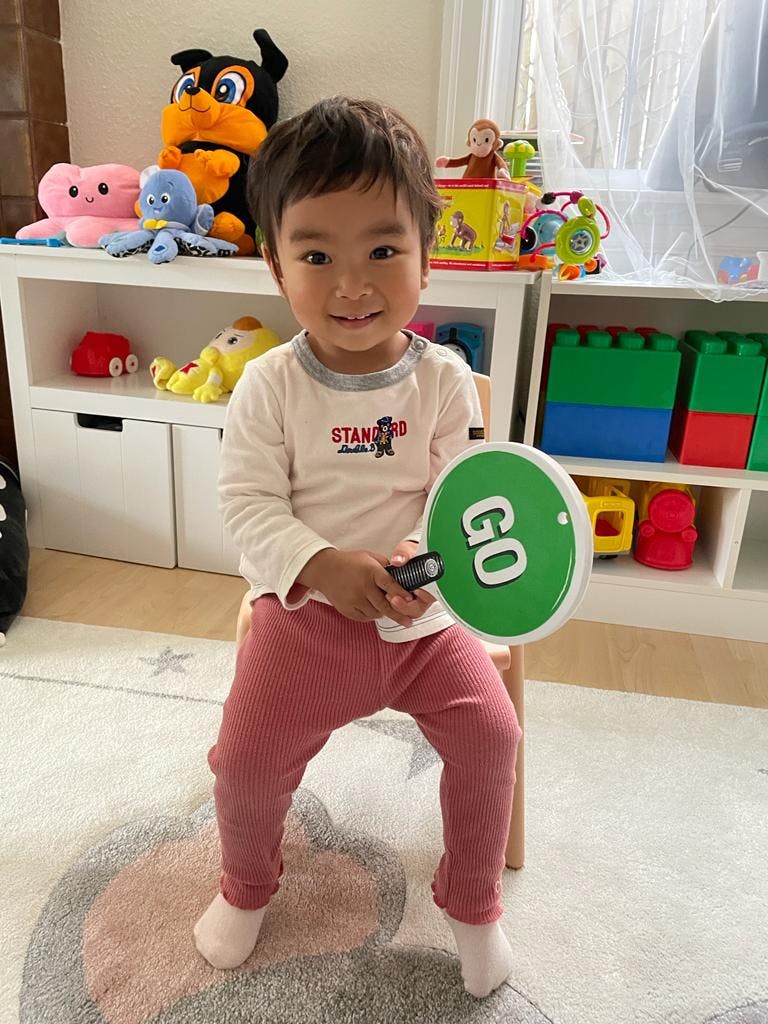 Child sitting and holding a green "GO" sign