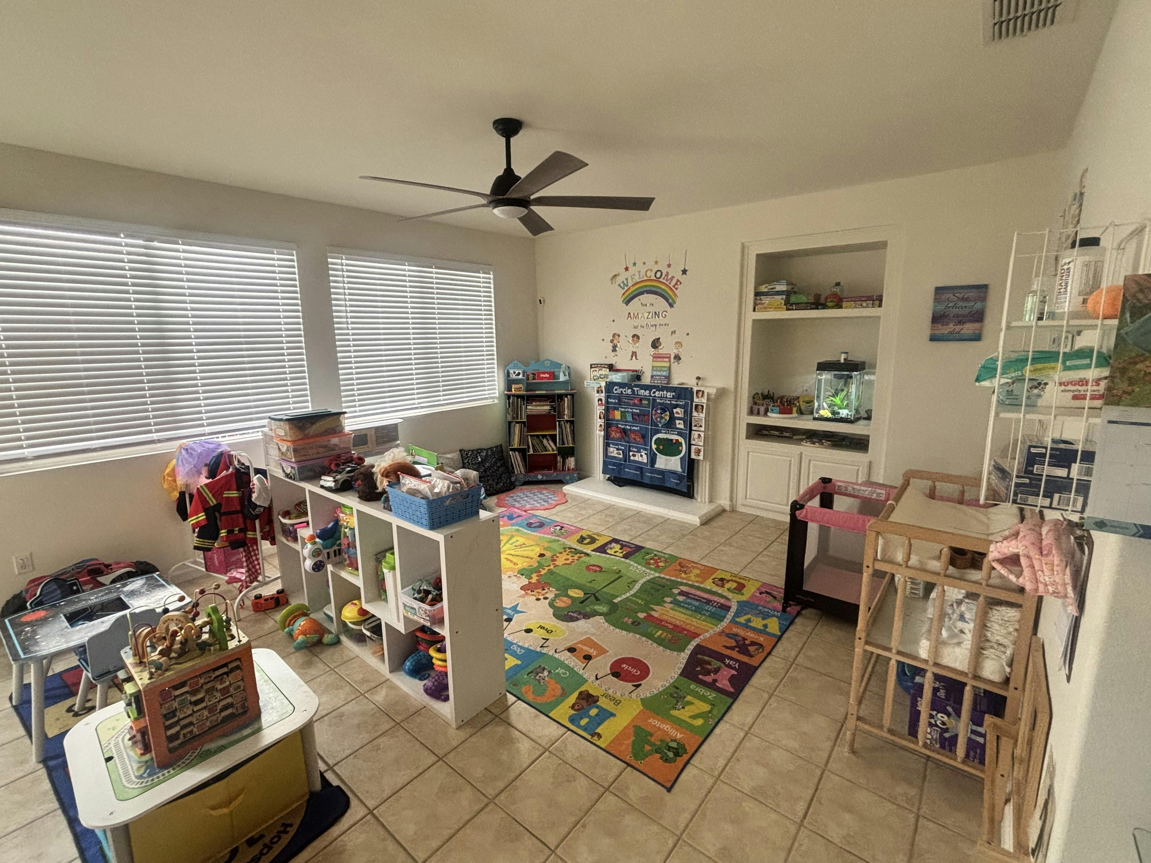 Children's play area with toys, a colorful rug, and a ceiling fan