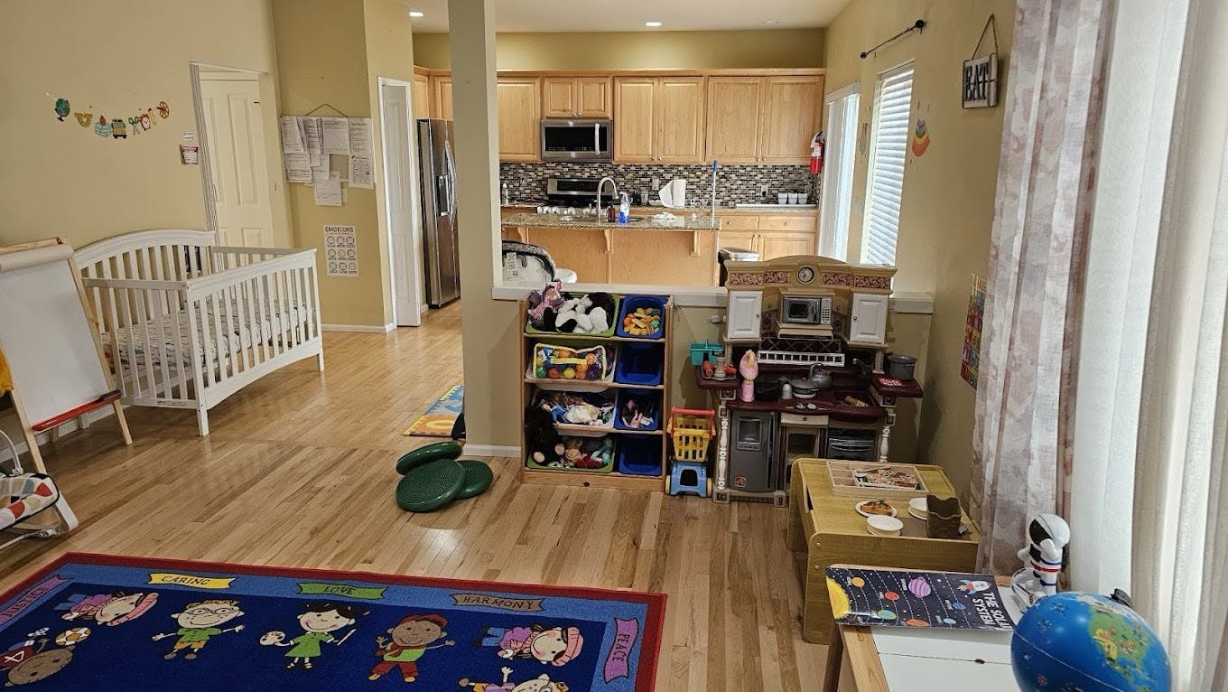 Crib and toys in a room with a kitchen in the background