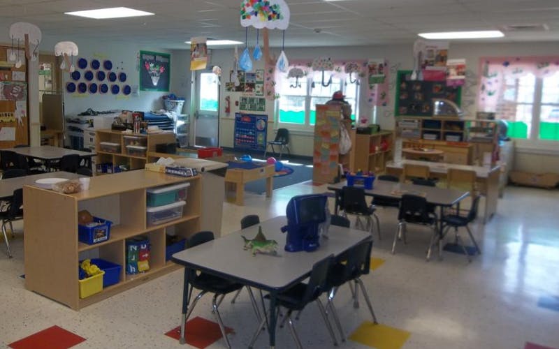 An empty classroom with tables, chairs, and shelves