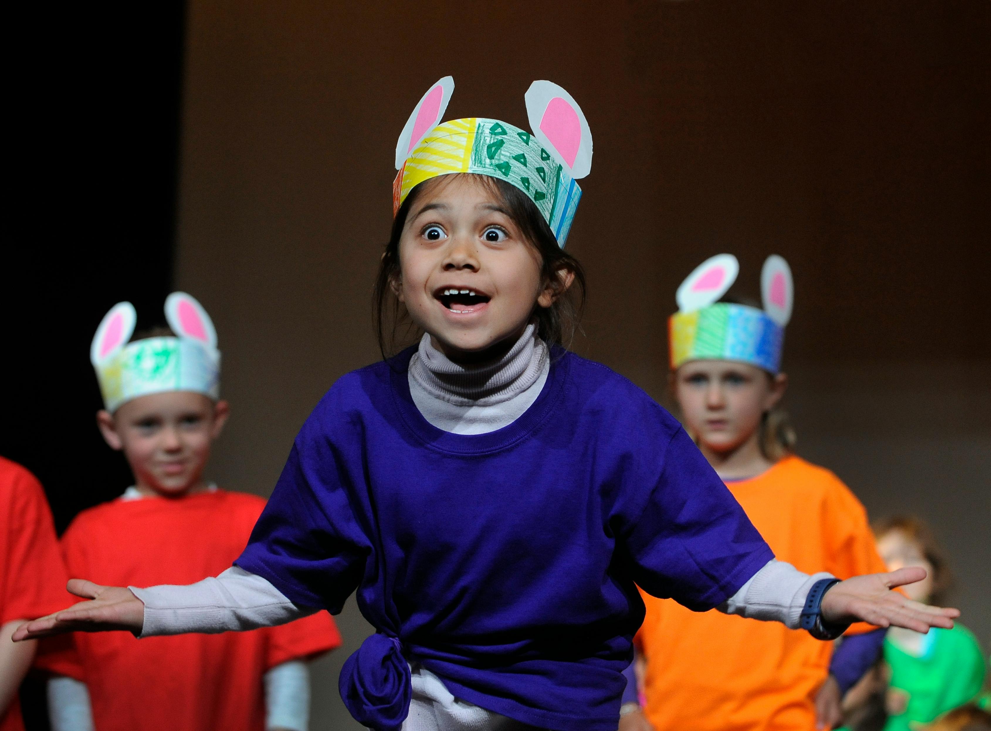 Child in a bunny ear headband performing with other children
