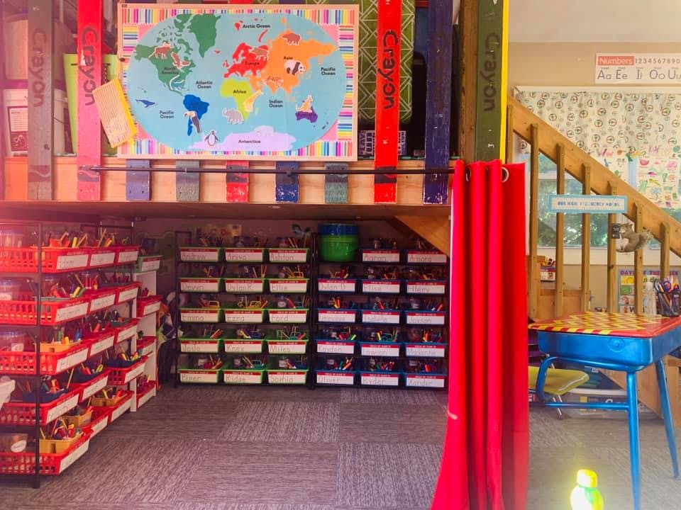 Classroom with world map, storage bins, and a small table