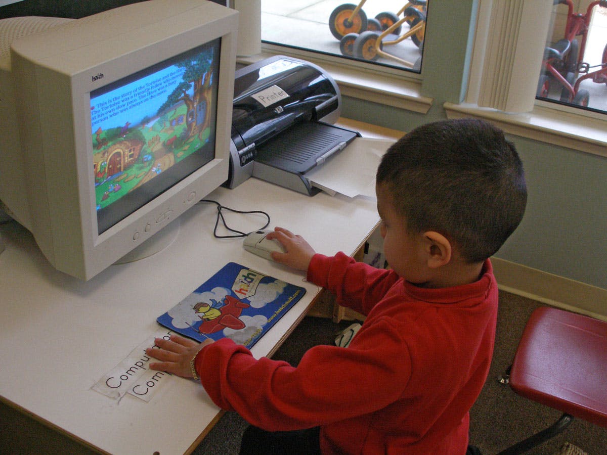 Child using a computer with a mouse and a colorful mousepad