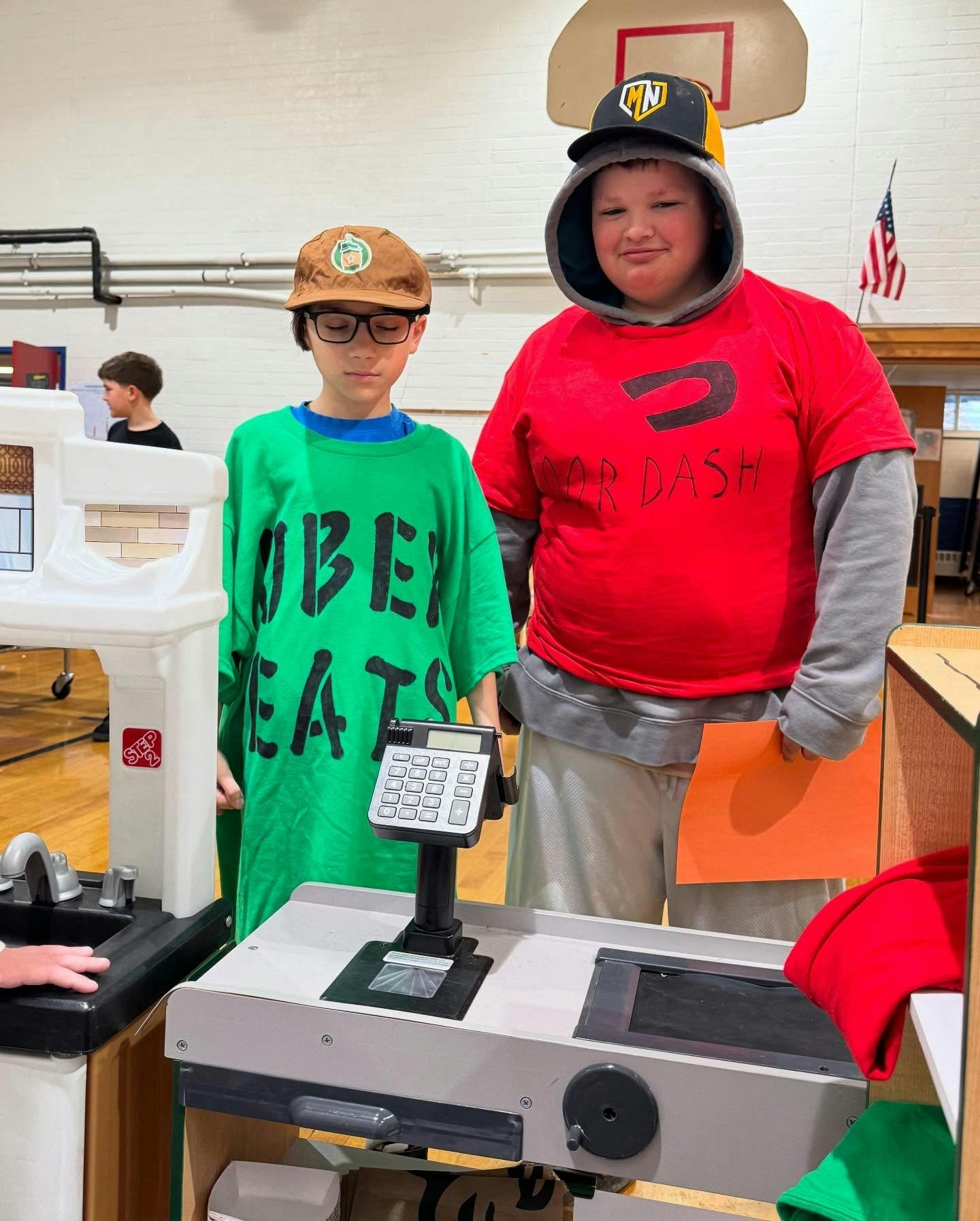 Two children standing behind a toy checkout counter
