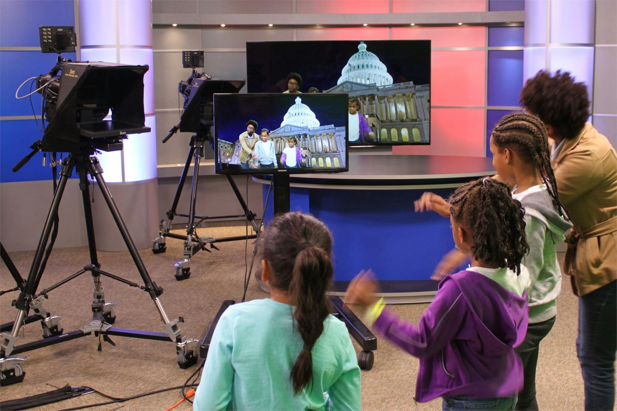 Children and an adult watching a screen in a television studio