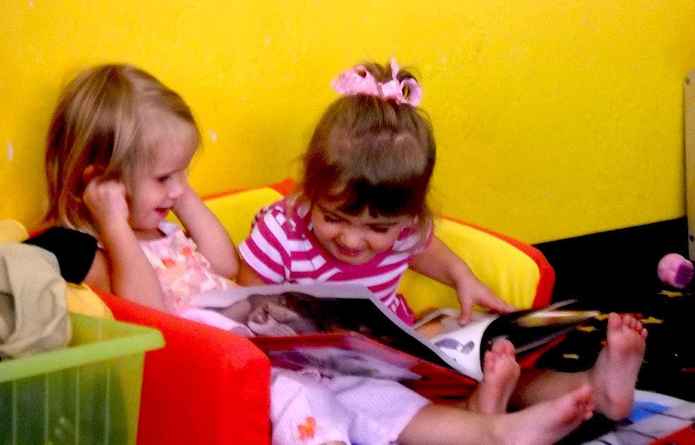 Two children sitting together and looking at a book