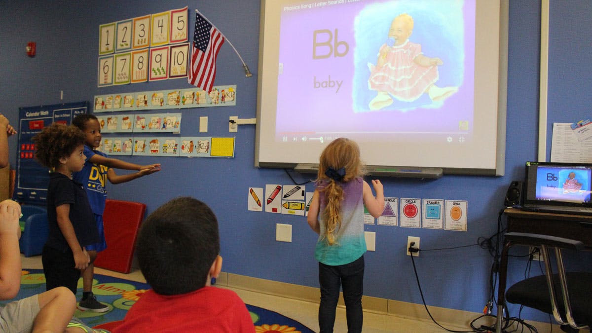 Children in a classroom looking at a projected image on a screen