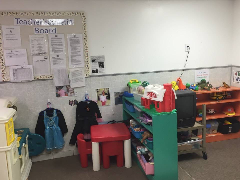 Classroom with a bulletin board, small red table and chairs, and toy shelves