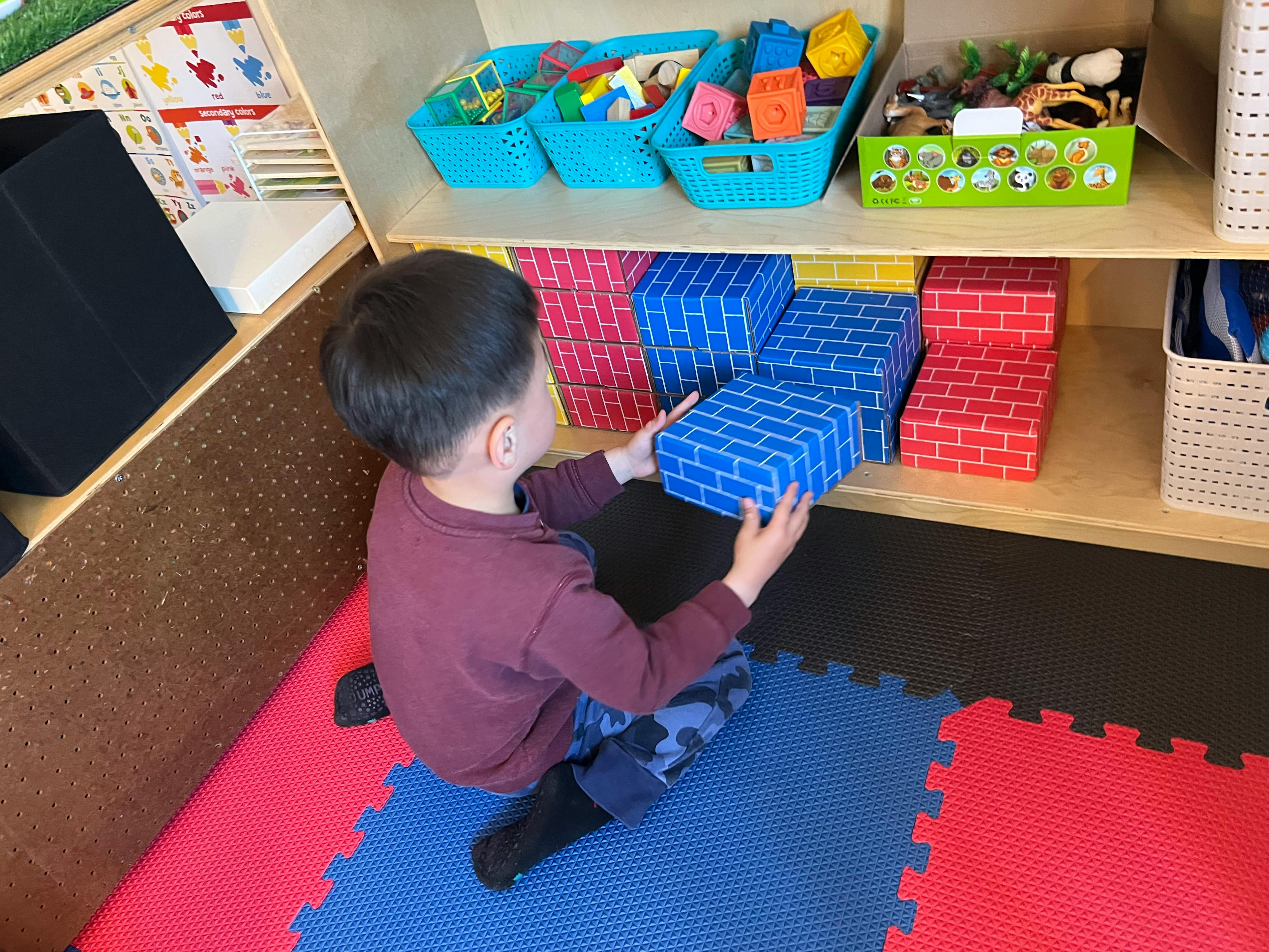 Child placing a blue block on a shelf