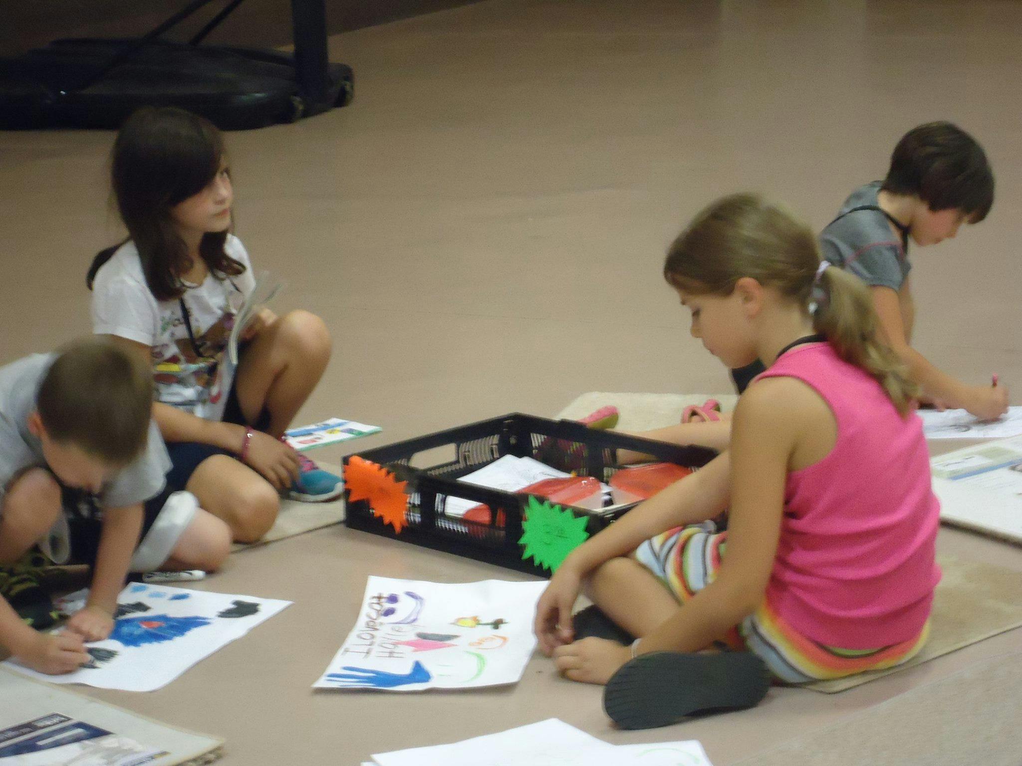 Four children sitting on the floor drawing