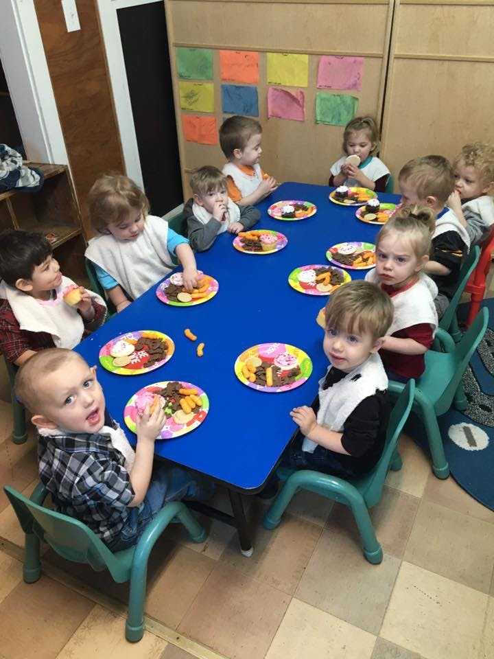 Children sitting at a blue table with plates of food