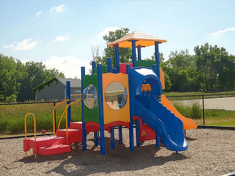 Colorful playground structure with slides and climbing elements on wood chips