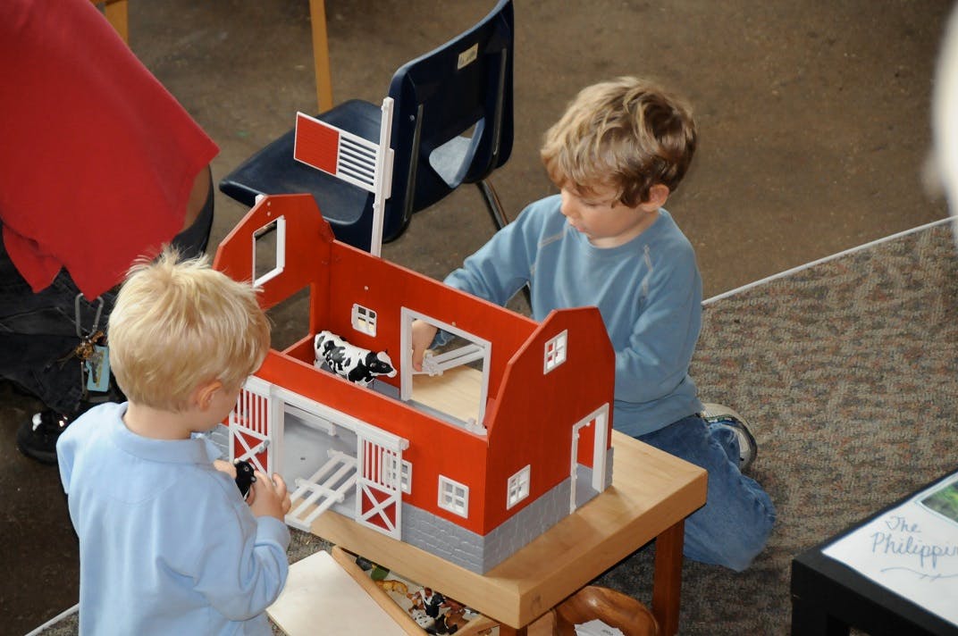 Two children playing with a toy barn