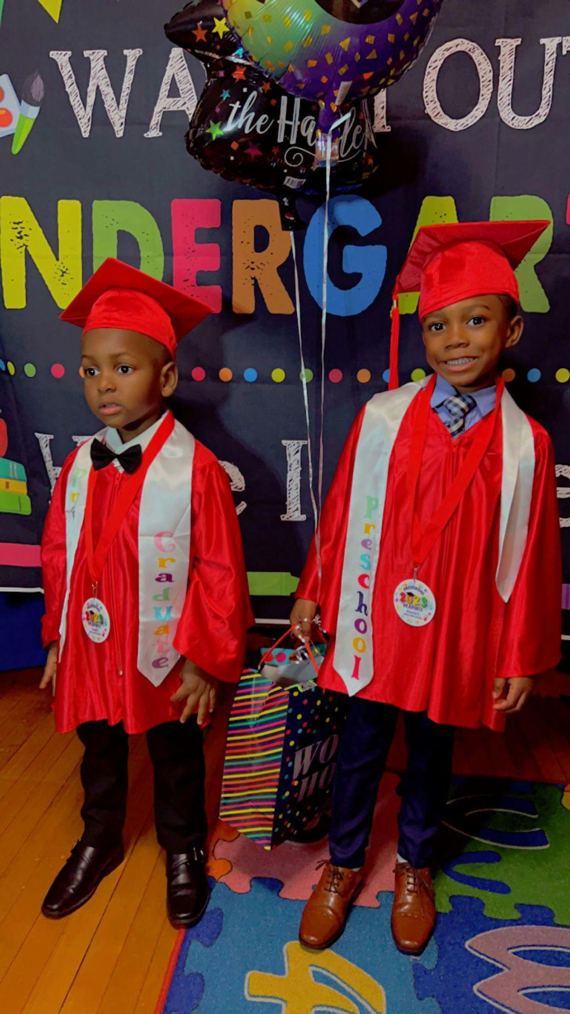 Two children in red graduation caps and gowns