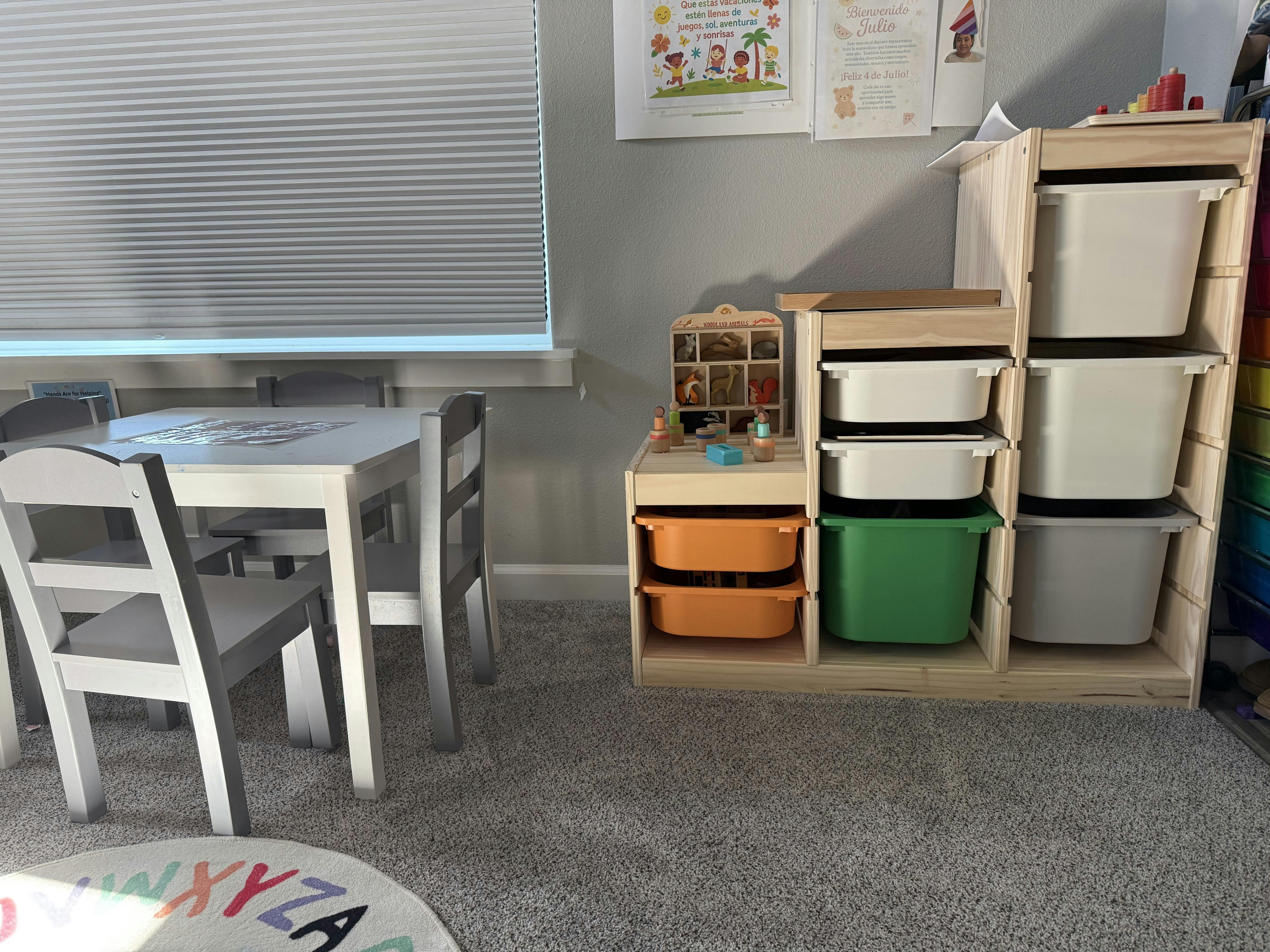 Child's table and chairs next to a storage unit with bins