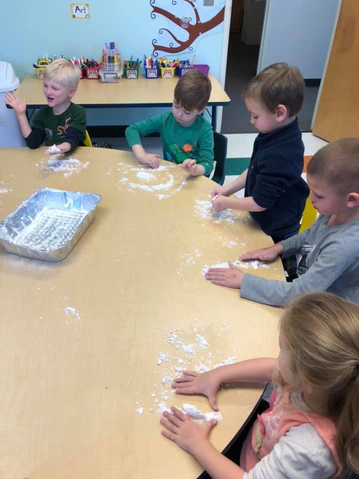 Children playing with white powder on a table