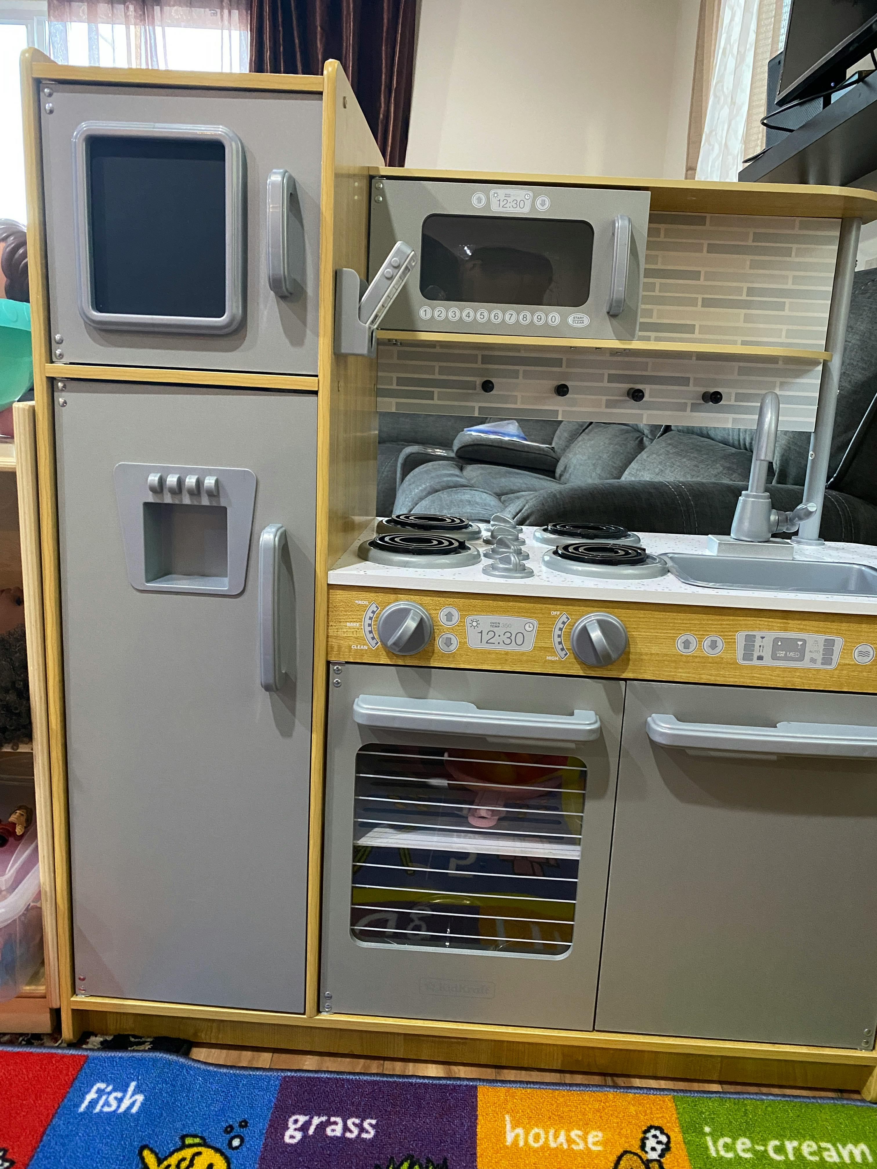 Child's play kitchen with refrigerator, microwave, stove, and oven