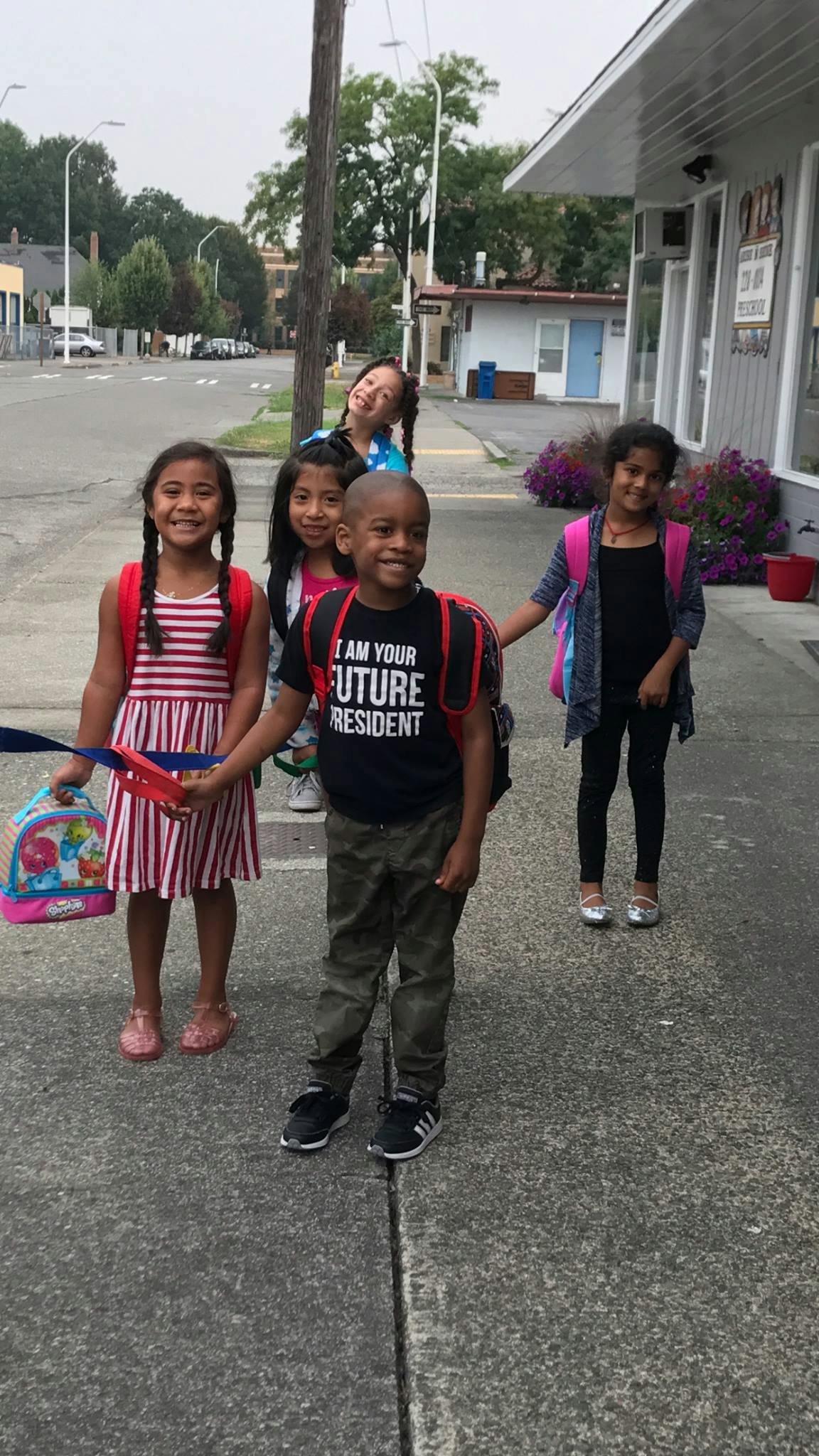 Children with backpacks standing on a sidewalk
