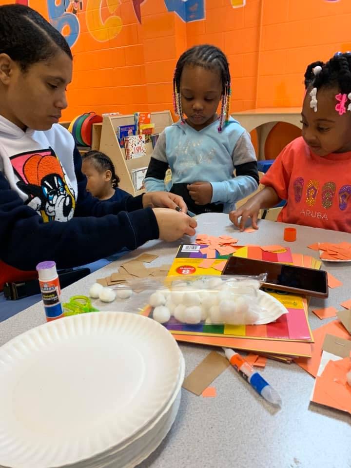 Person and two children doing crafts at a table
