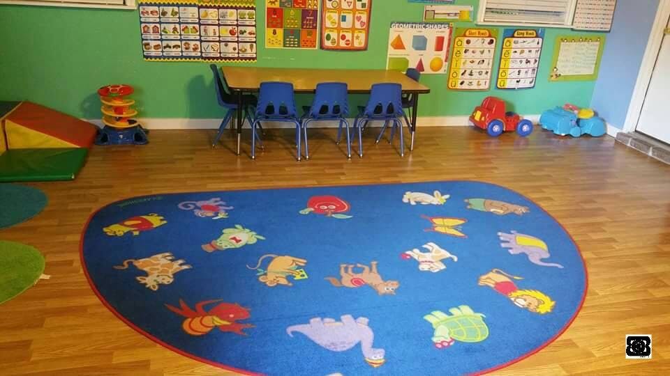 Playroom with a blue rug, small table and chairs, and toys