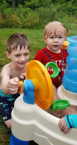 Two children playing with a water table