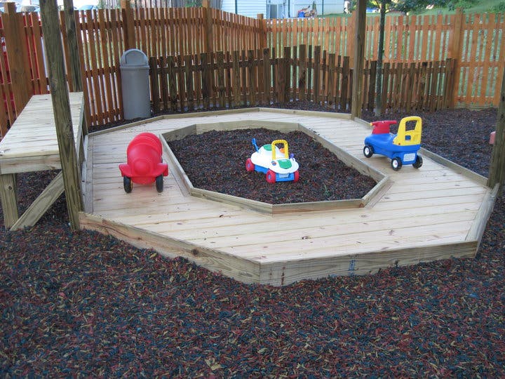 Playground with wooden sandbox and ride-on toys