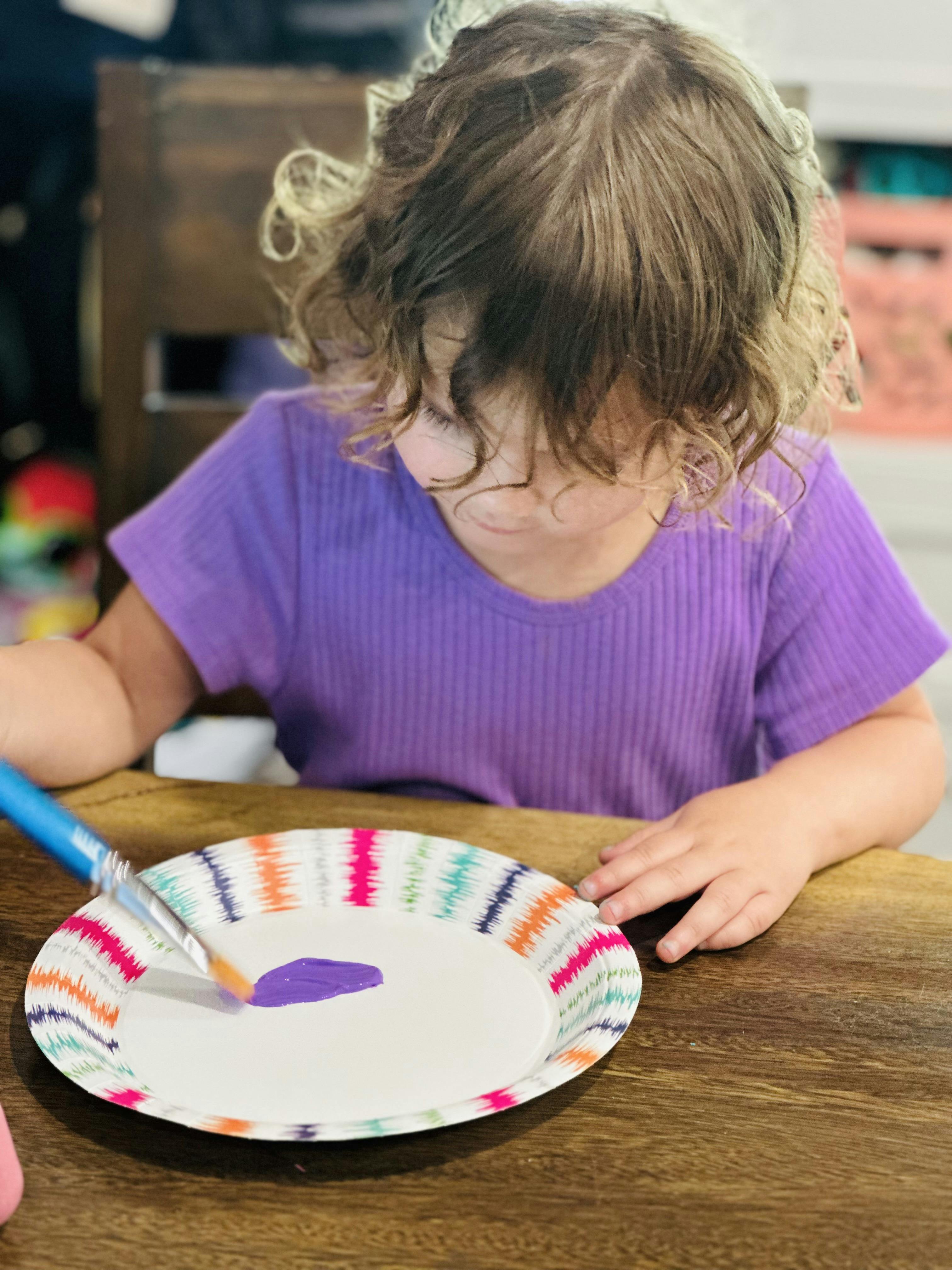 Child painting on a paper plate