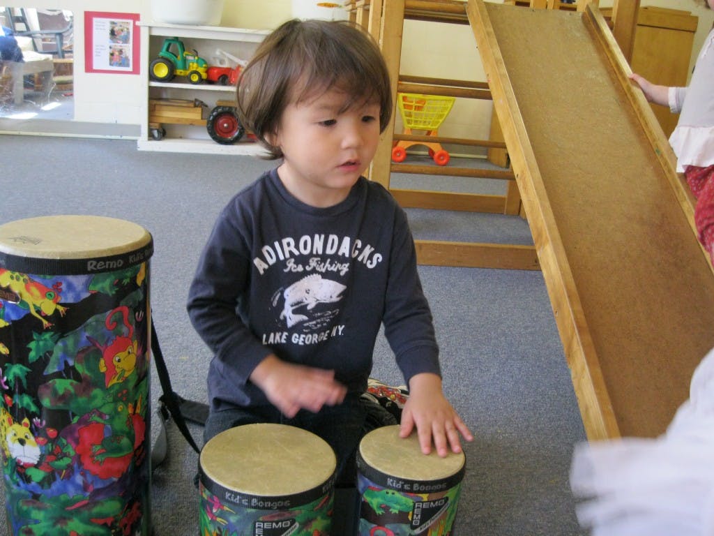 Child playing bongo drums in a classroom