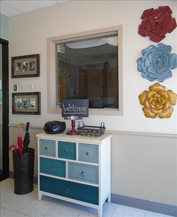 A console table with a welcome sign and umbrellas by a window