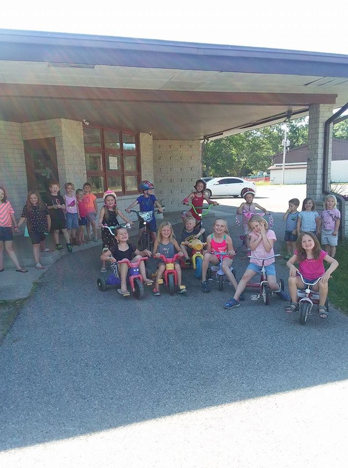 Group of children and teens with tricycles and bicycles outdoors