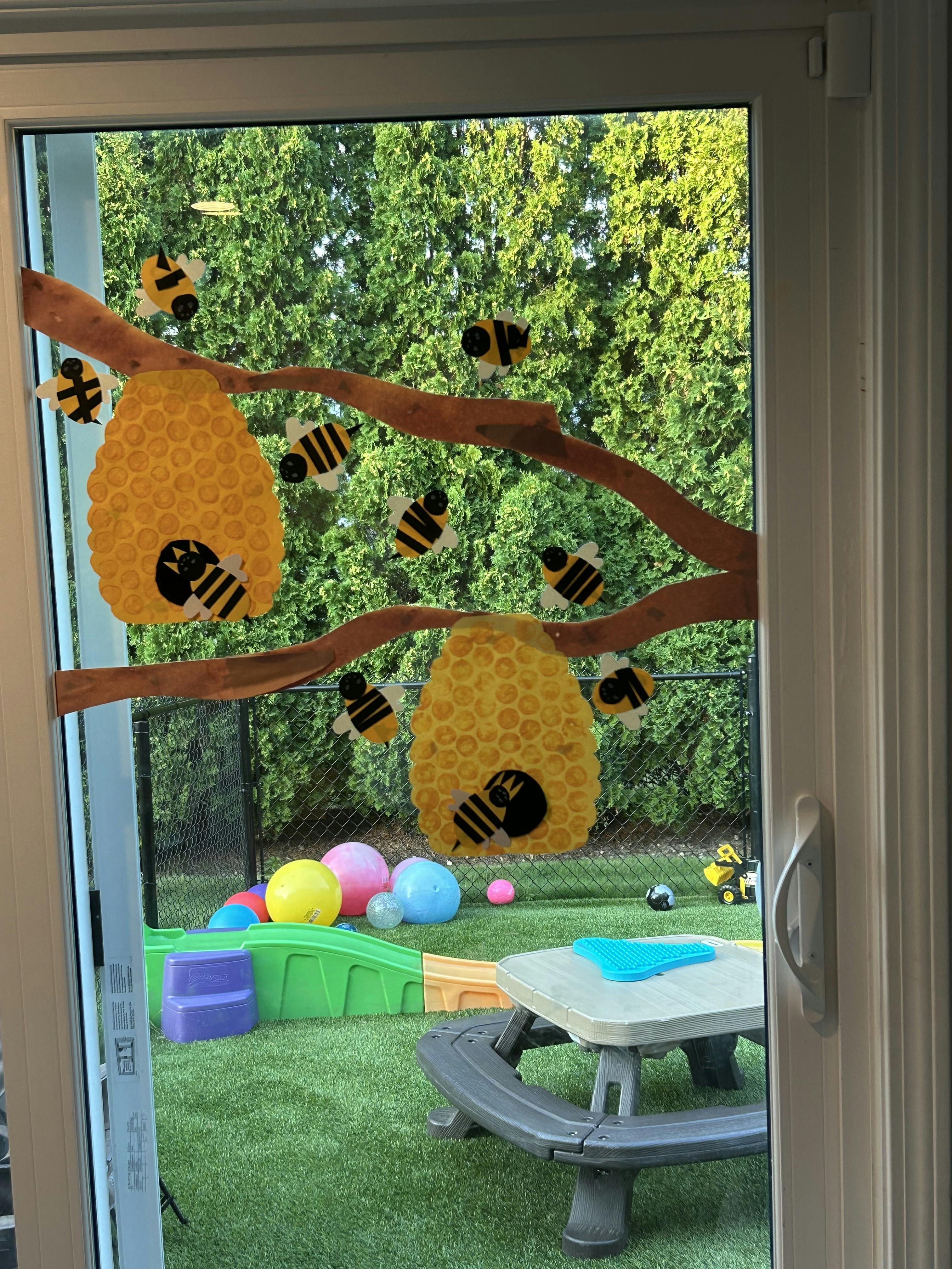 Beehive and bee decorations on a window overlooking a backyard