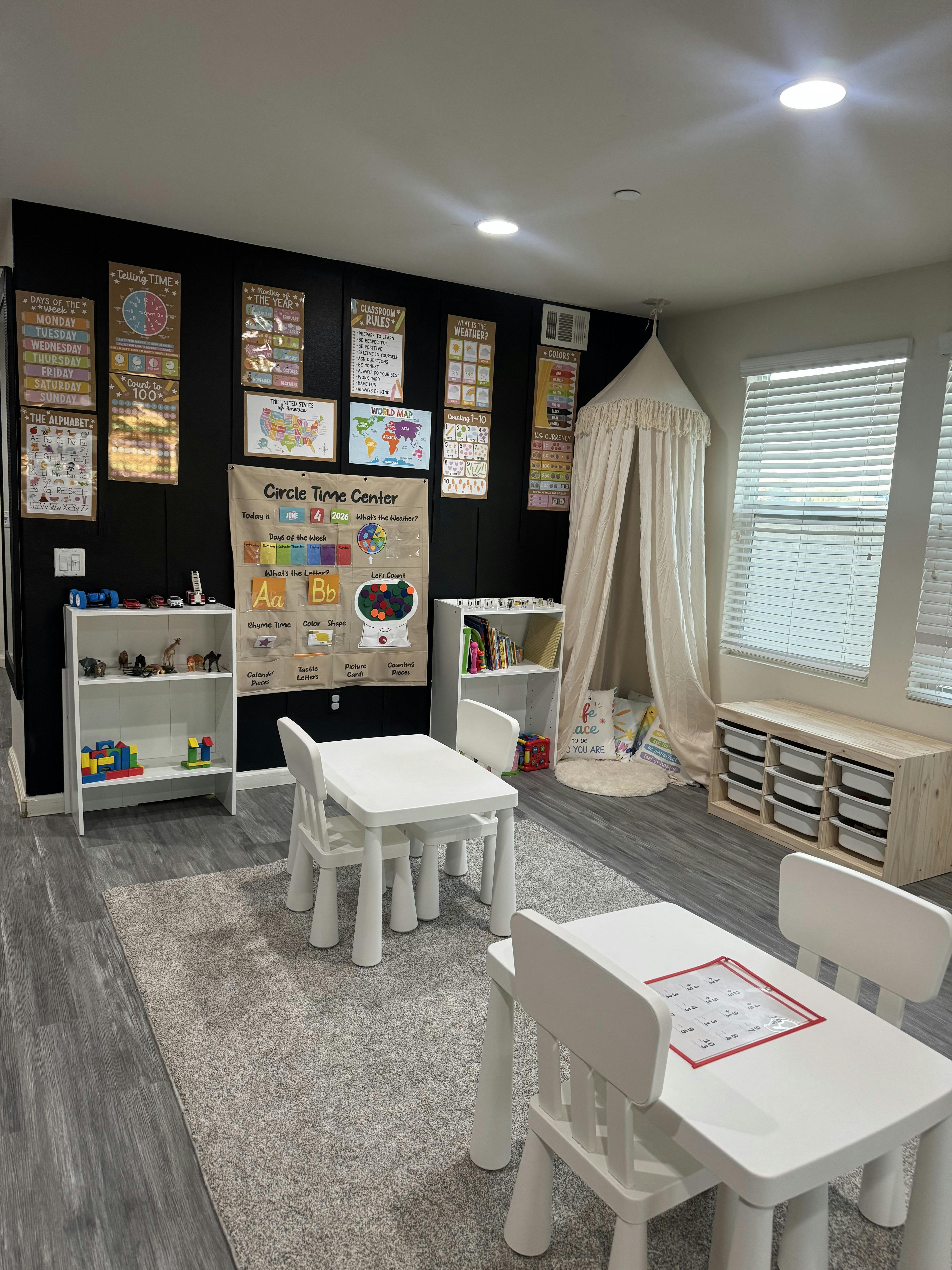 Classroom interior with educational wall posters, tables, chairs, and play tent