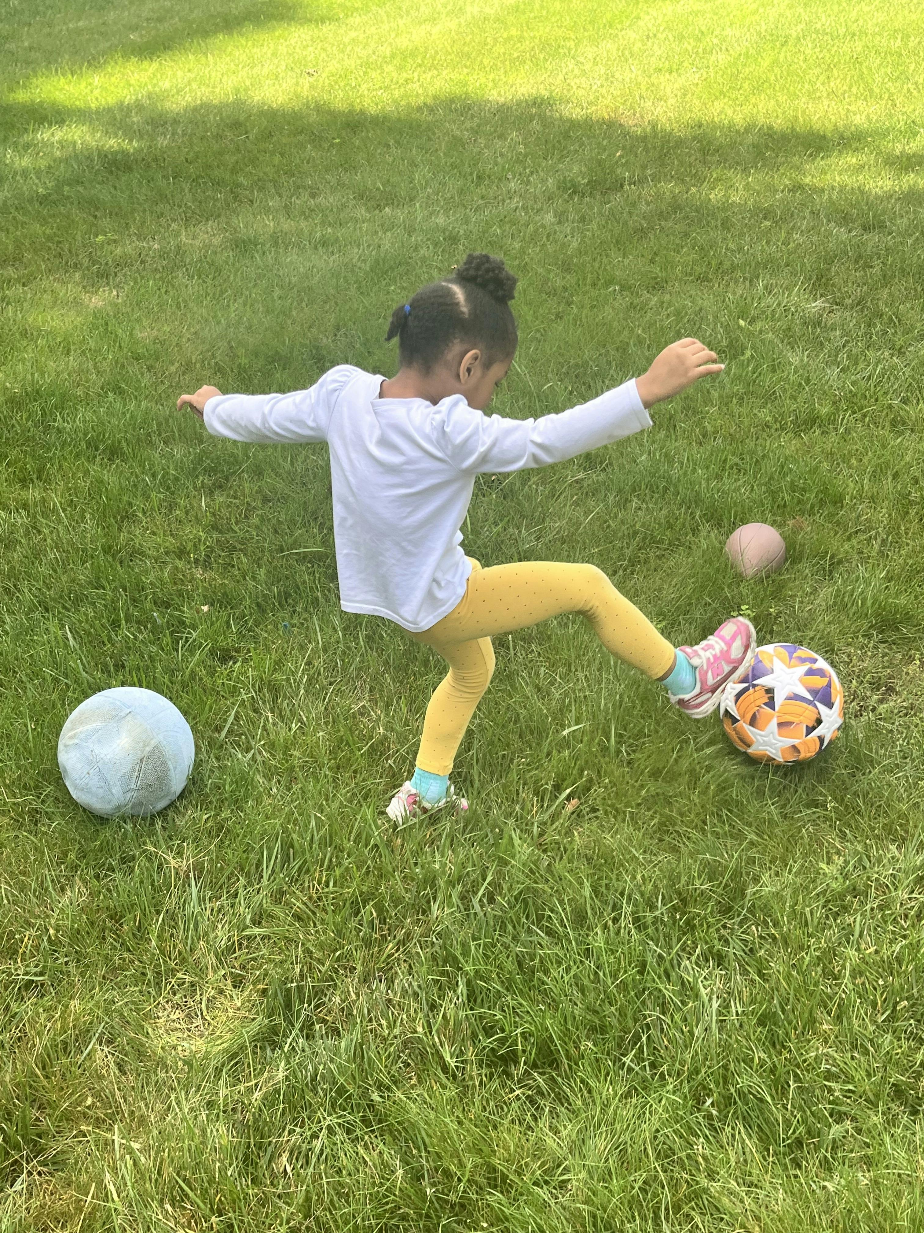 Child kicking a soccer ball in the grass