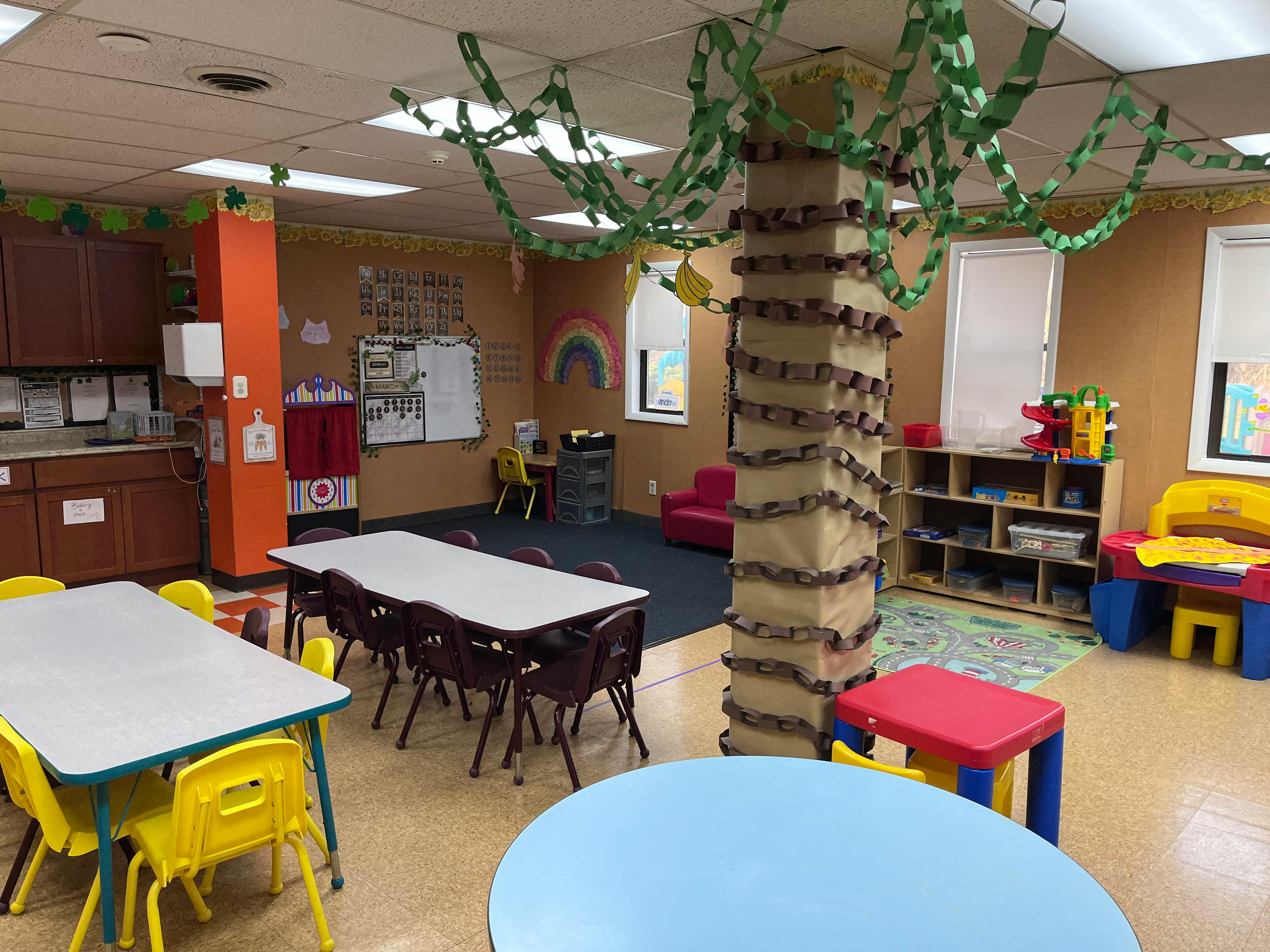 Classroom with tables and chairs, decorated pillar, and play area