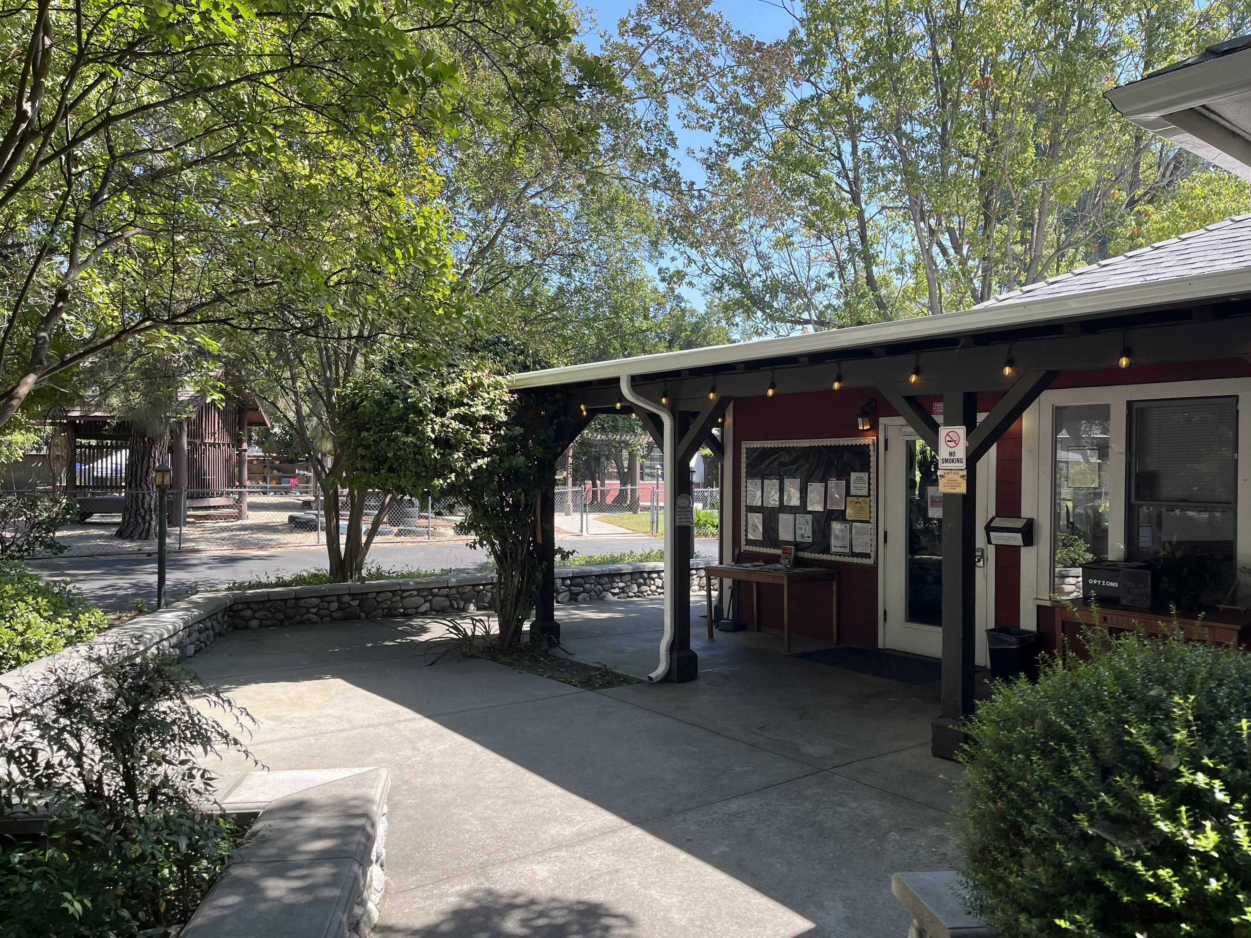 Entrance to a building with a red facade, covered patio, and information board