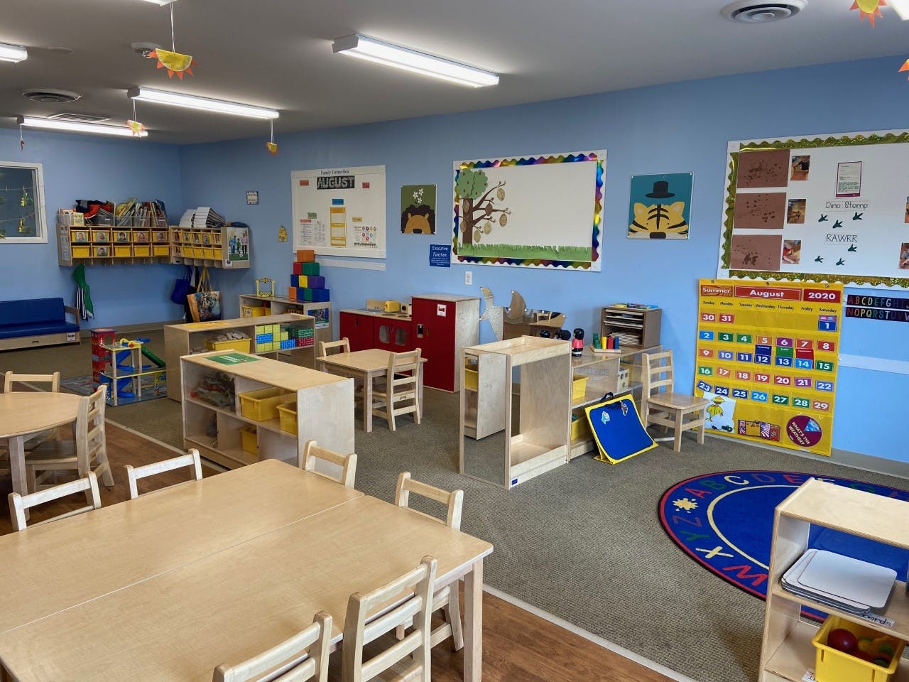 Empty colorful classroom with small tables, chairs, and learning materials