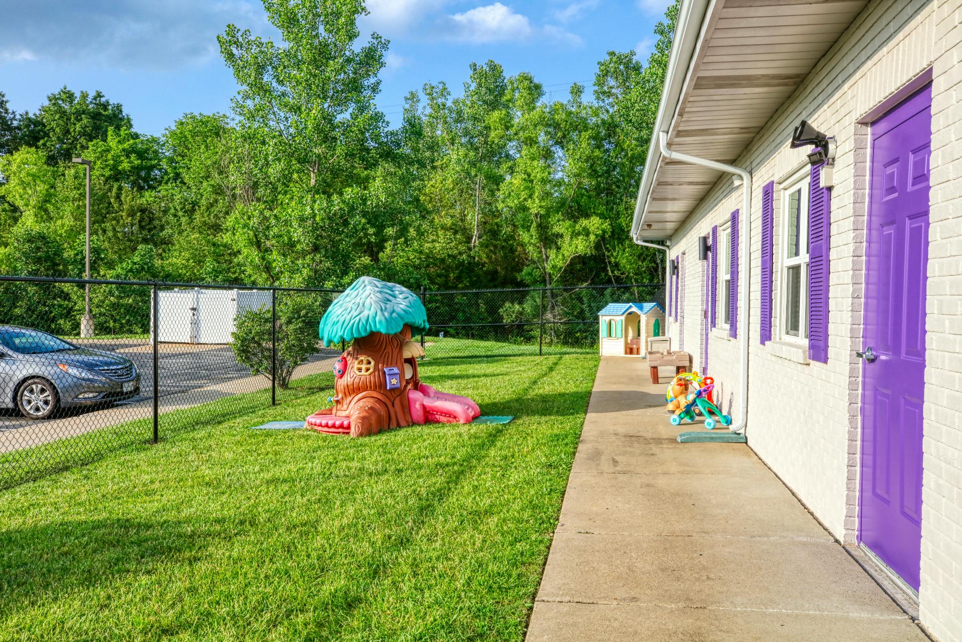 Playground with a treehouse slide and play structures next to a building