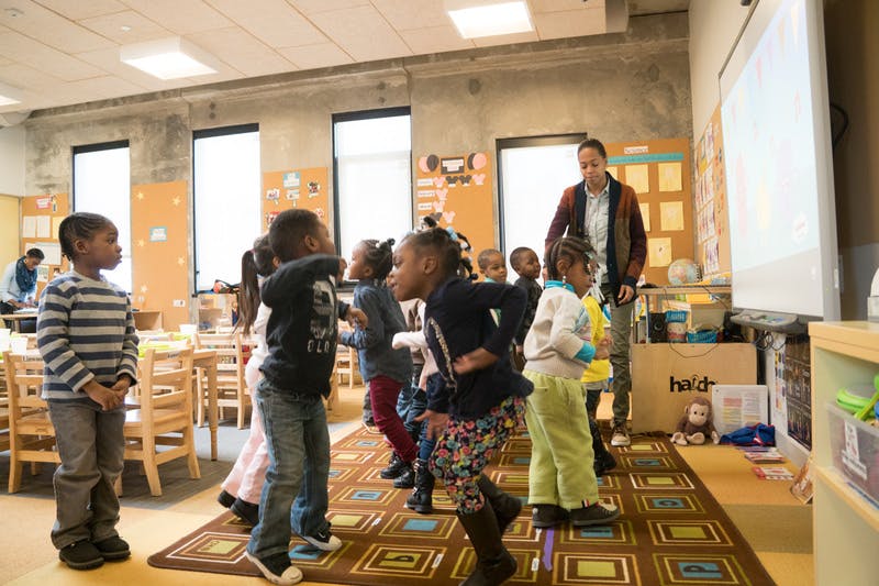 Children and an adult standing in a classroom