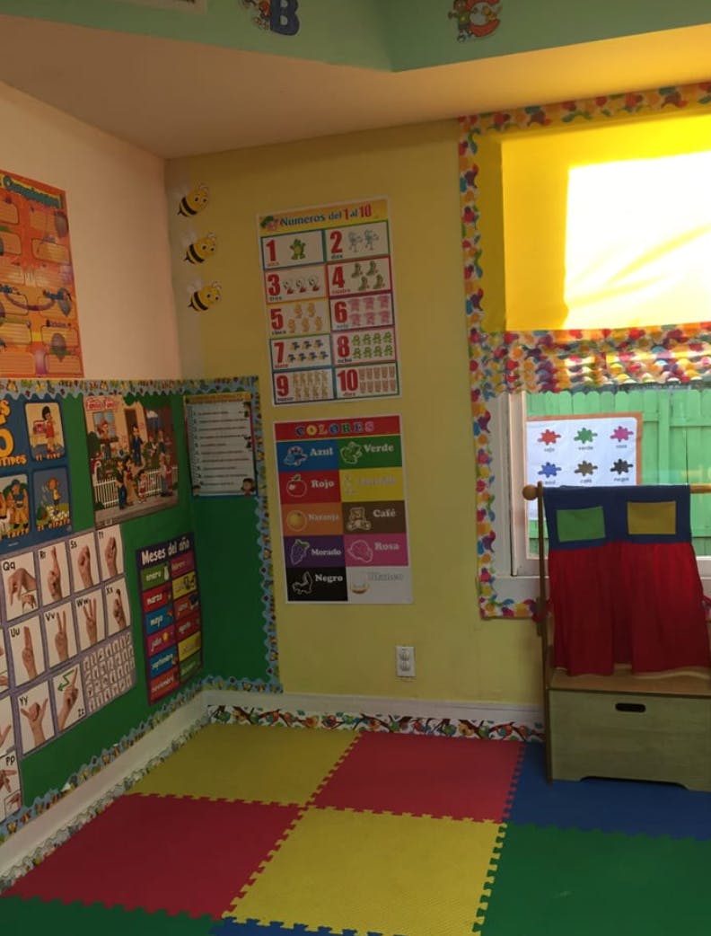 Classroom with colorful floor mats, educational posters, and a puppet theater