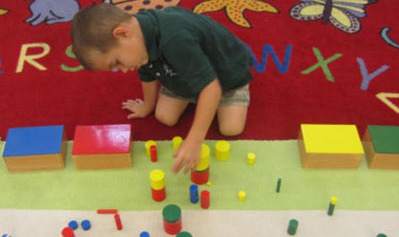 Child on knees playing with colorful blocks on a rug