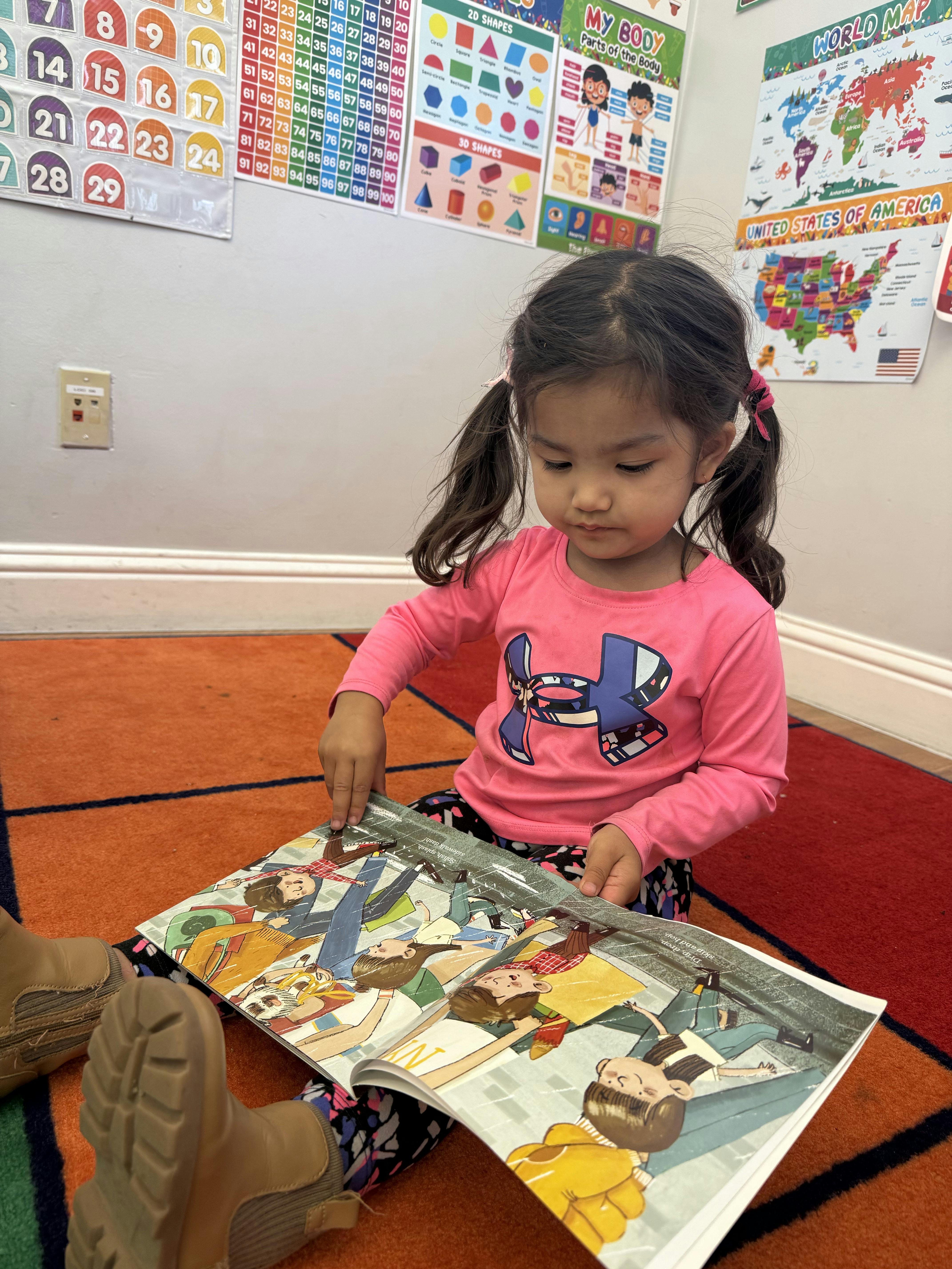 Child sitting on a rug, looking at an open book