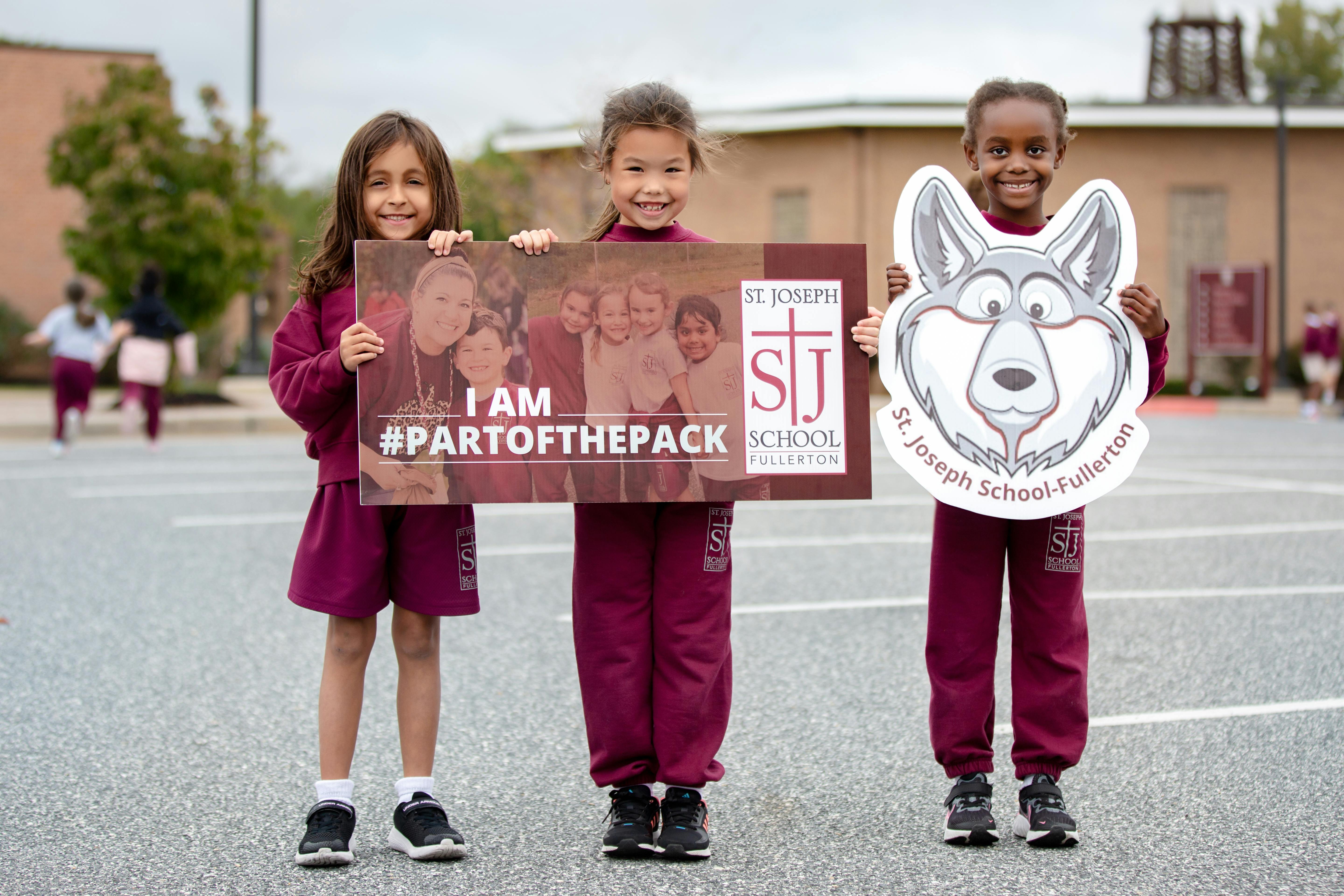 Three children holding signs, one with "I am #partofthepack"