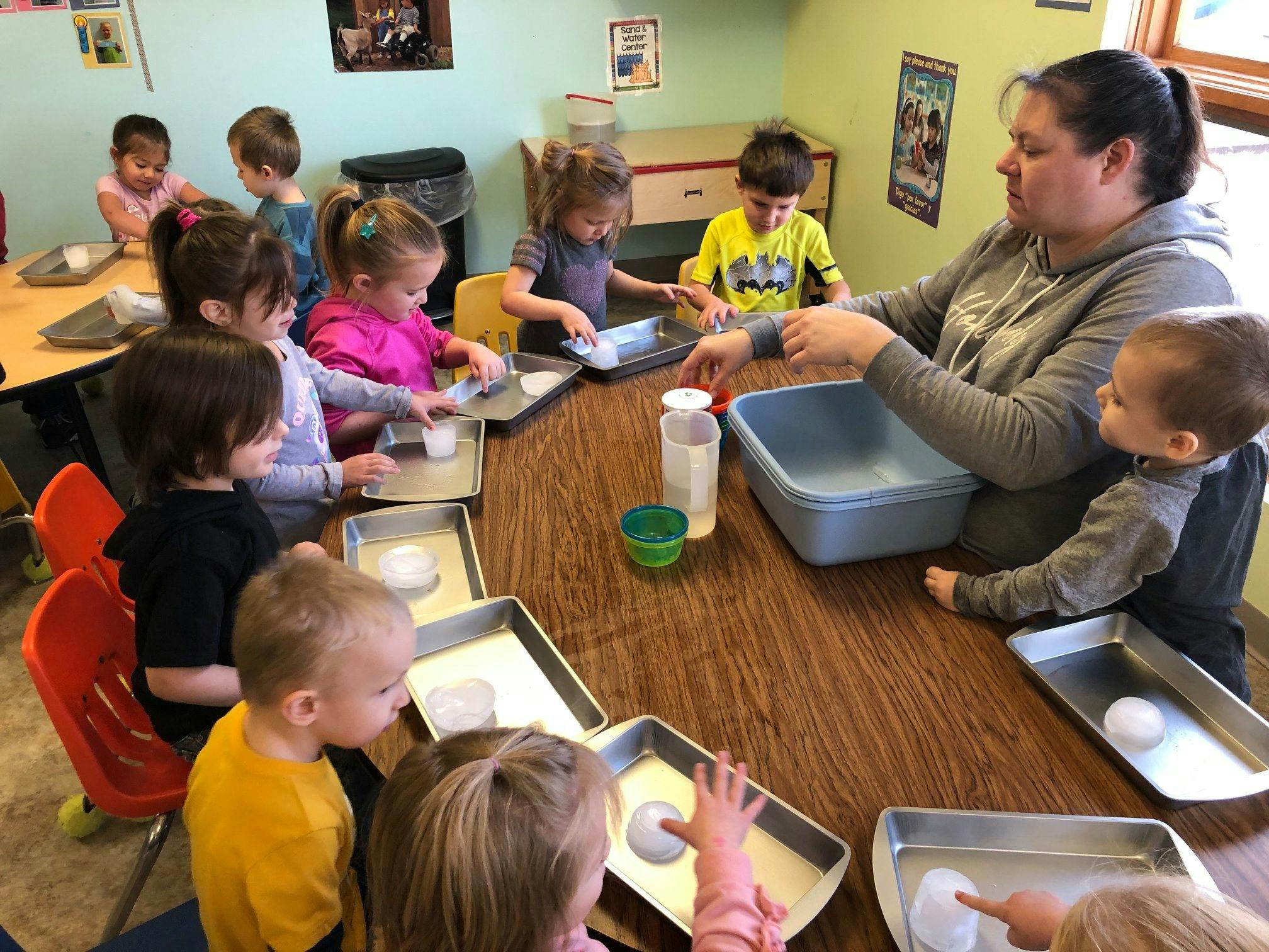 Adult and children at a table with trays and containers