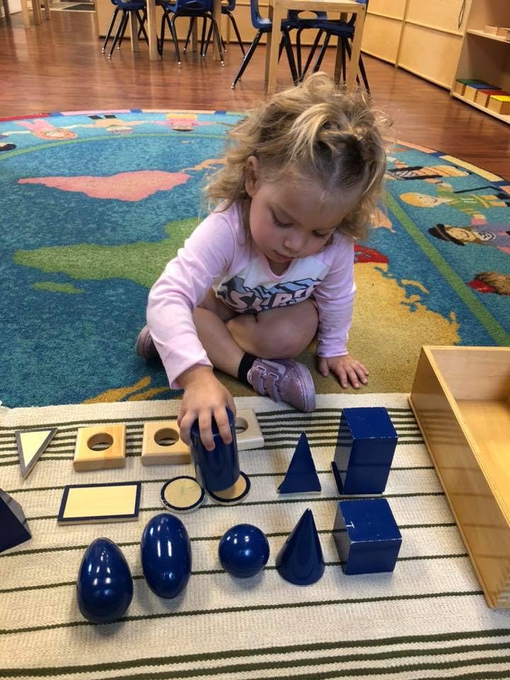 Child playing with geometric shape blocks on a rug