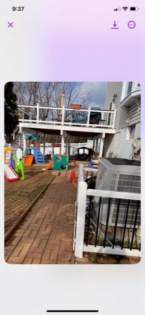 Backyard with a brick path, children's play equipment, and a two-story deck