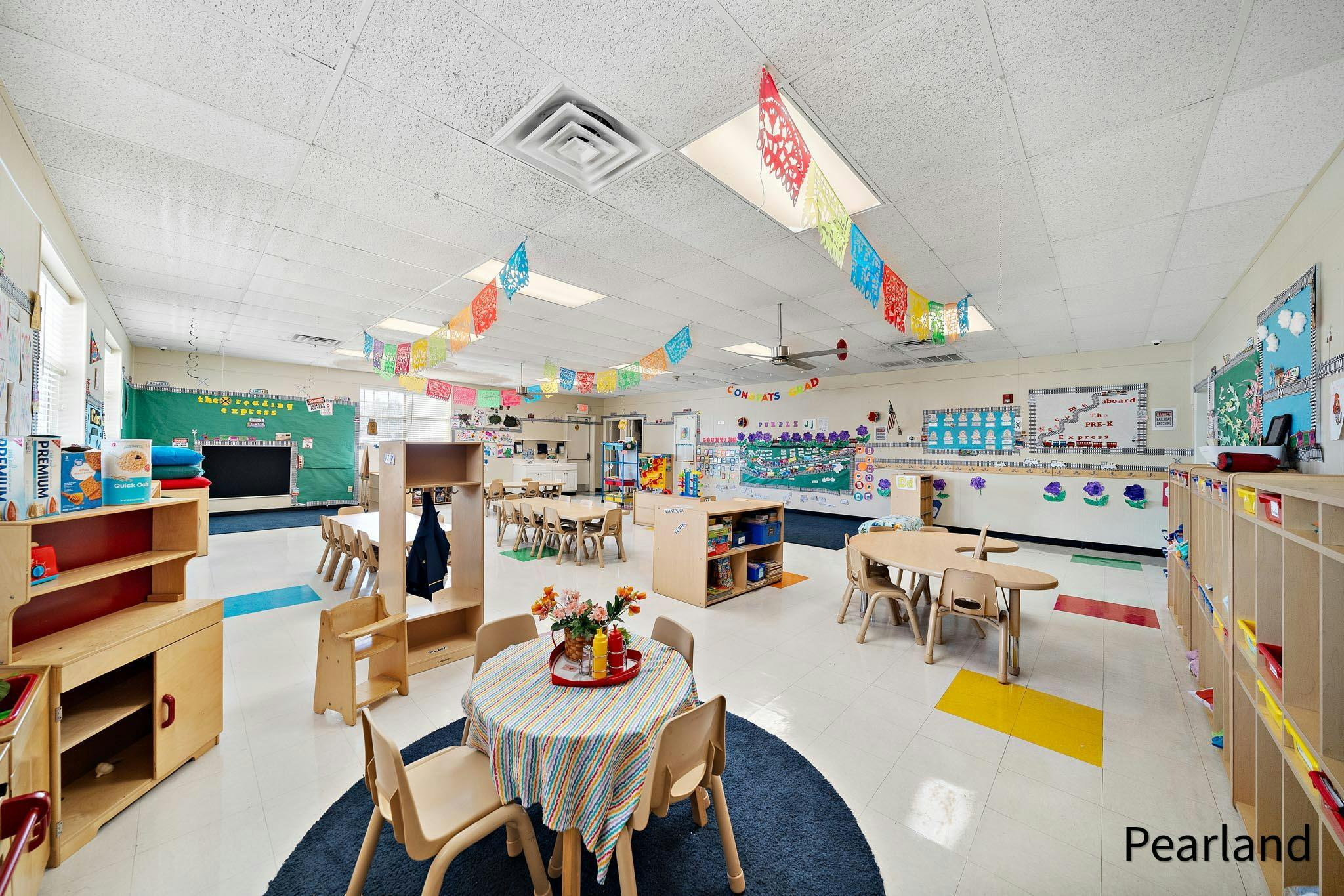 Empty classroom with small tables and chairs, decorated with colorful banners